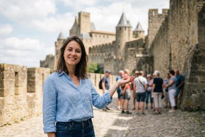 Jeune femme souriante guidant des touristes près des remparts